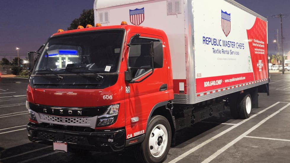 Red Rizon cab-over electric box truck with a Republic Master Chefs-branded cargo box parked in a lot at night.
