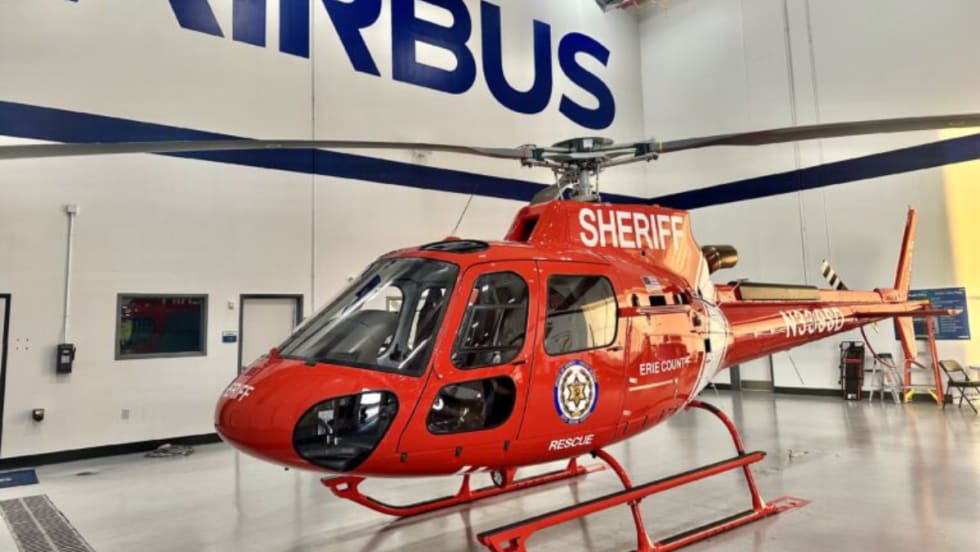 A newly delivered red Airbus H125 helicopter marked “Sheriff” and “Erie County” inside an Airbus facility.