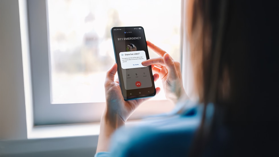 over shoulder view of woman holding phone and making an emergency call and sharing video
