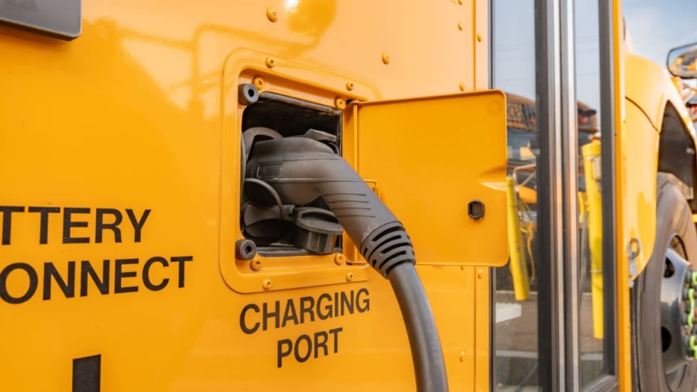 Close-up of an electric school bus charging port with a charging cable connected.