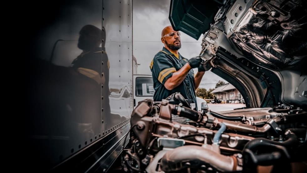 Truck technician working with hood open
