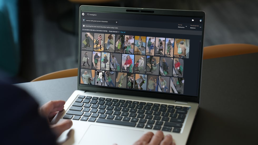 Image of a persons hands on keyboard of laptop with screen that displays multiple images from security cameras