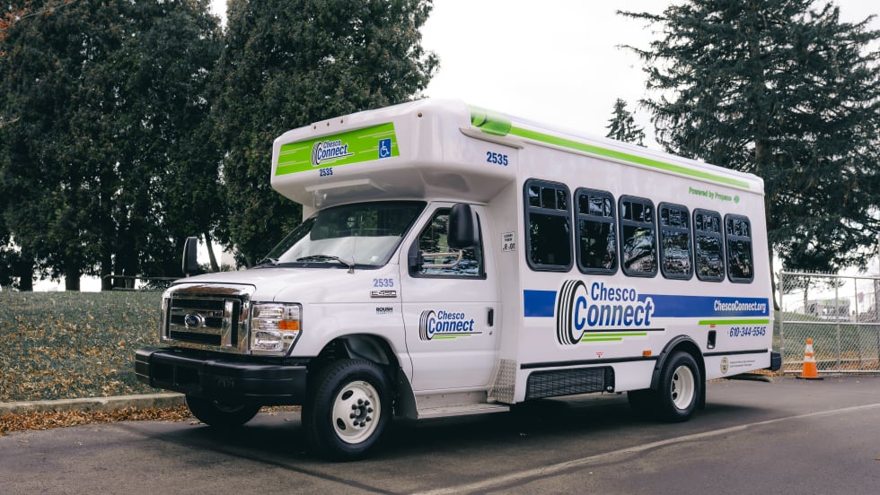 A white Chesco Connect paratransit bus parked outside.