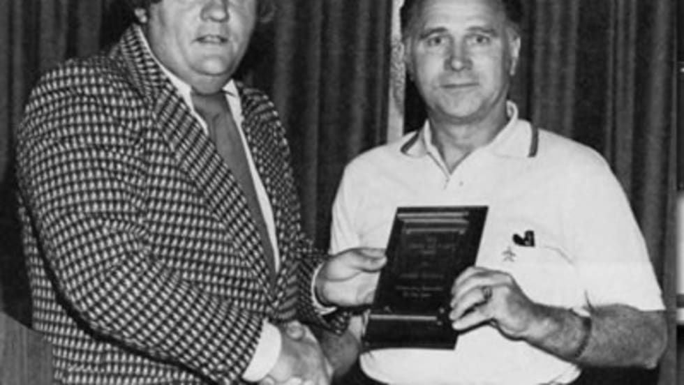 two men pose with an award