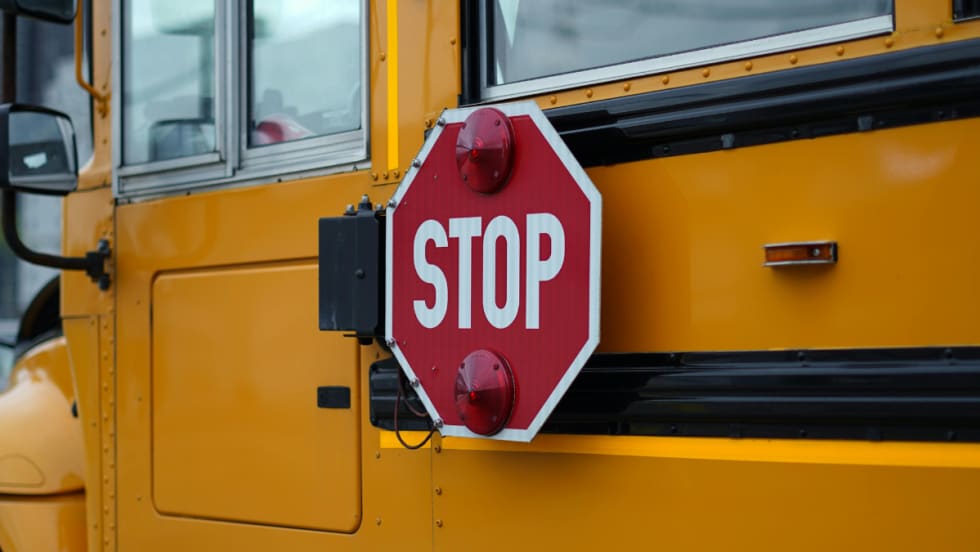 The side of a school bus with a retracted stop signal.