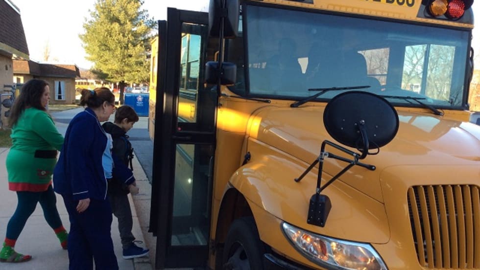 three people board a school bus