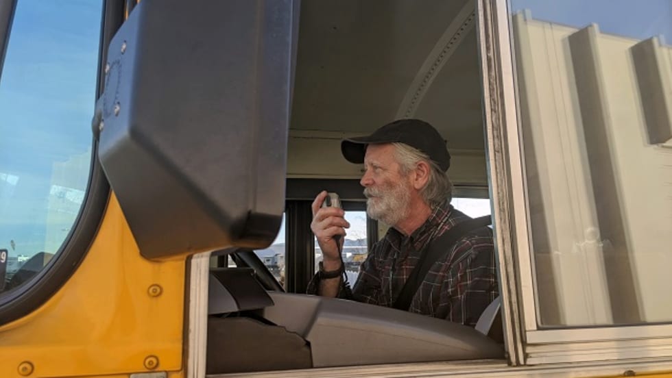 a man drives a school bus and talks through the radio