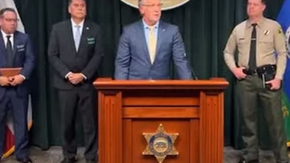 Law enforcement press conference with officials at podium with sheriff's badge