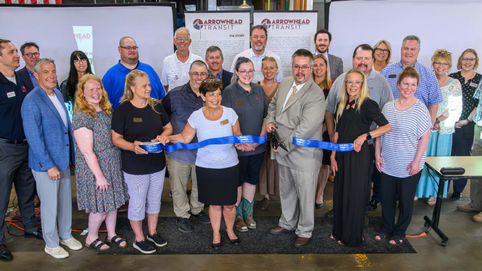 Business and community members pose during a ribbon cutting.