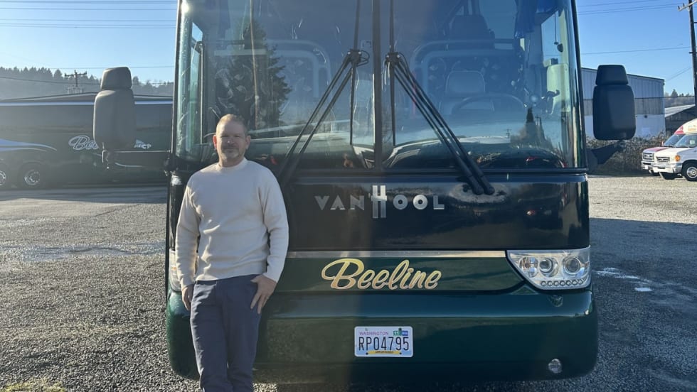 Buslane Founder and CEO Michael Rogers poses in front of a charter bus.