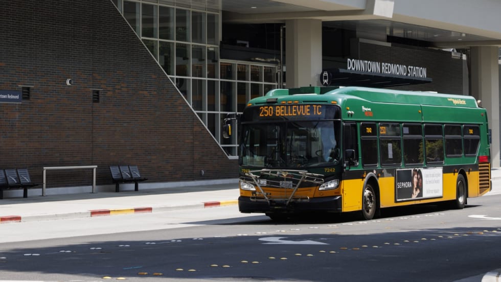 A green and yellow King County Metro bus outside a station.
