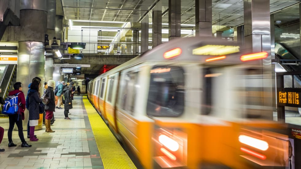 An MBTA Orange Line passenger train driving through a station.