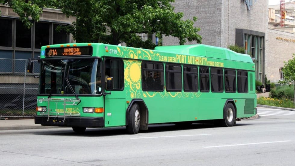 A bright green PRT bus on a city street.