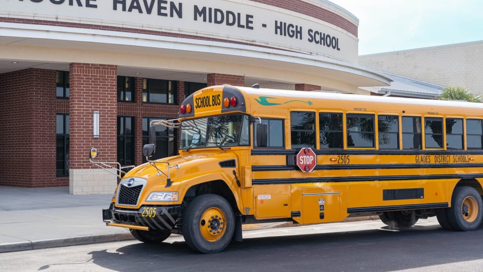 an electric school bus in front of a school