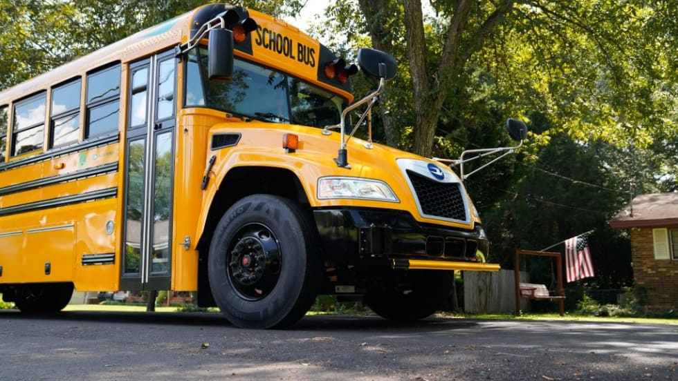 a school bus on a road with trees in the background