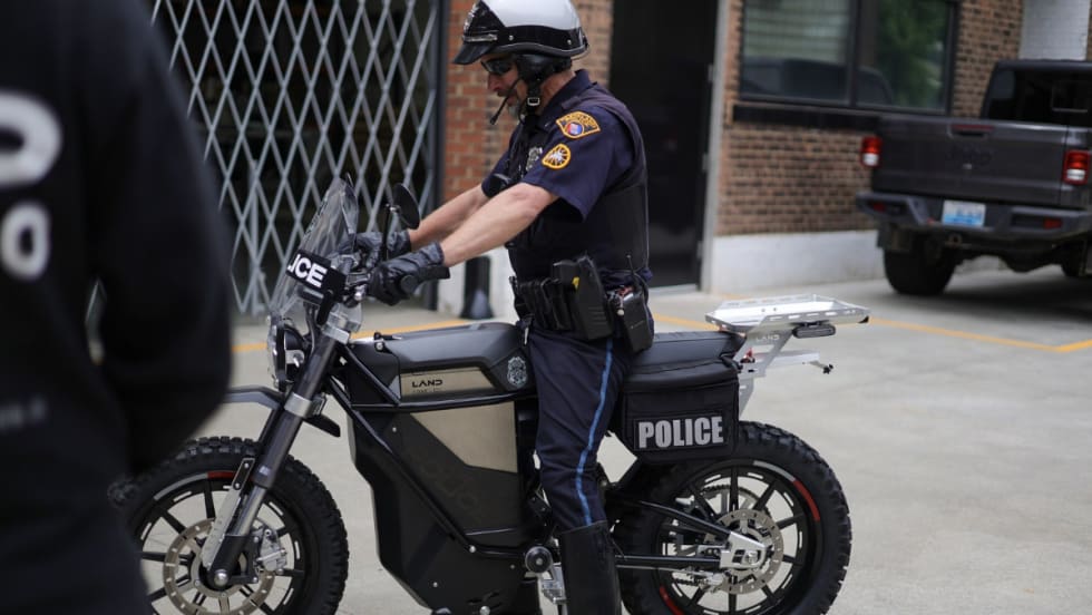 An officer sits on a silver and black e-bike called The District.