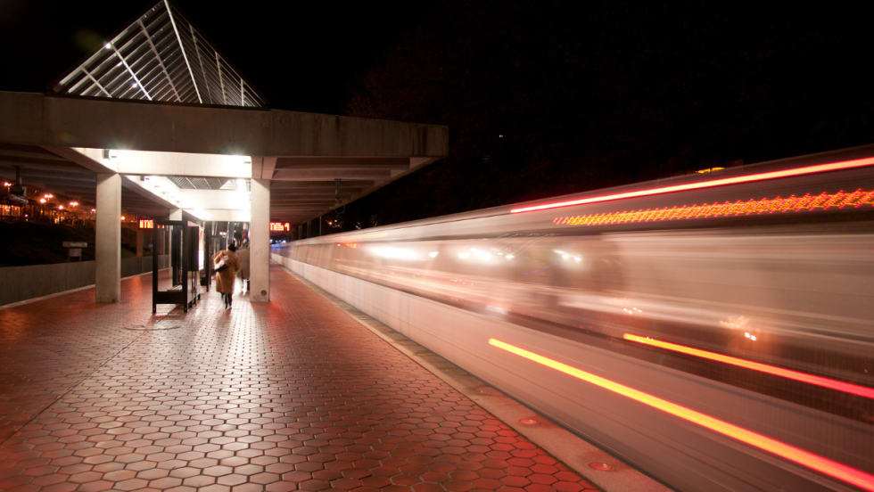 Light trails of a passenger train passing by a station at night. 