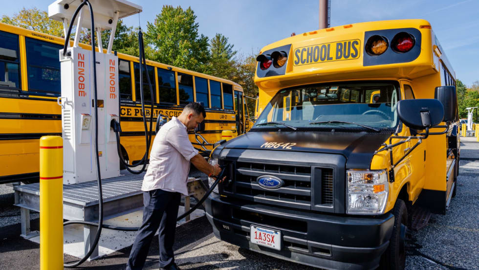 A man connecting a Zenobē charger to a school bus.