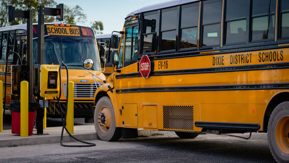 two school buses park in ev charging spots