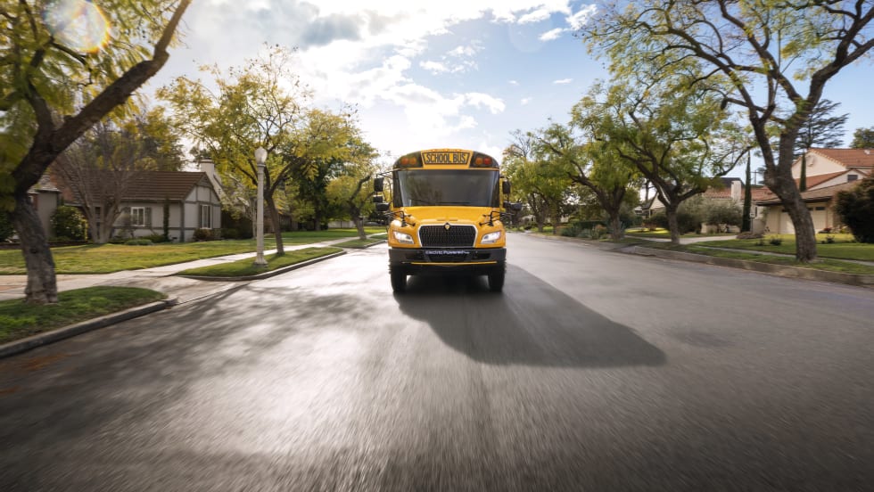 Front view of an IC Bus next generation electric CE Series bus driving on a suburban street.