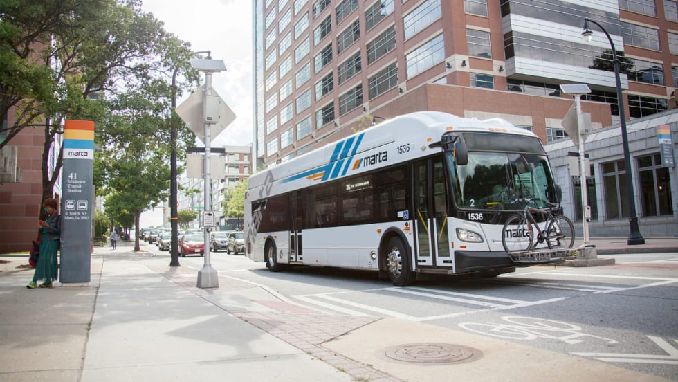 A white MARTA public transit bus near a bus stop.
