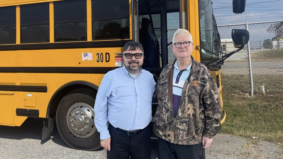 two men stand in front of a school bus in tennessee