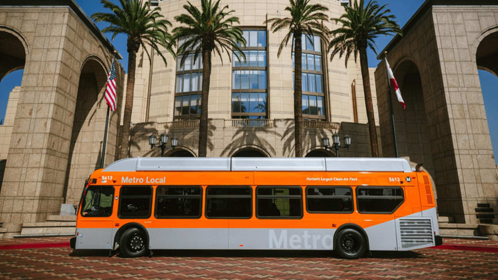 Side view of an orange LA Metro bus parked outside. 