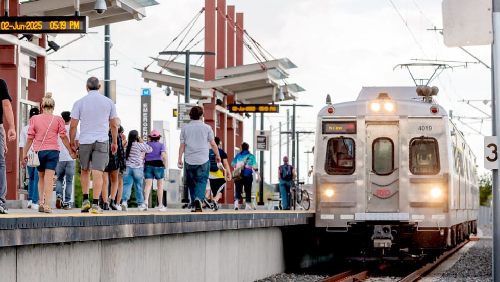 Riders walk down an outdoor rail line platform for the Regional Transportation District in Denver, Colorado.