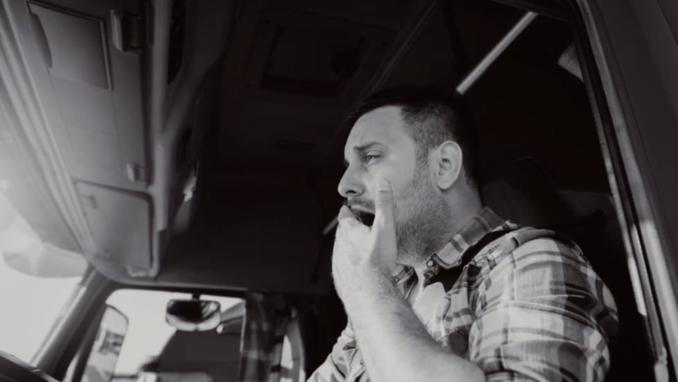 Truck driver yawning behind wheel