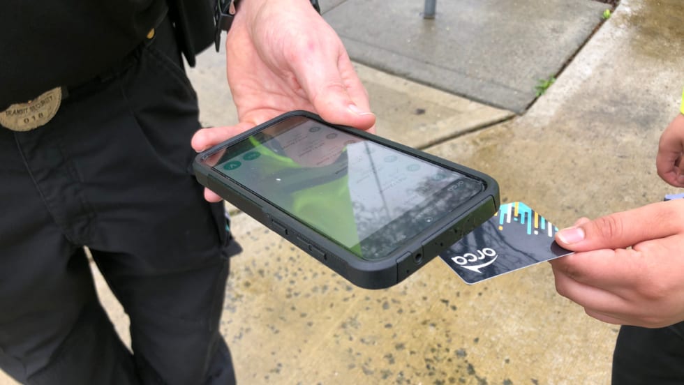 A rider tapping their ORCA card with a fare enforcement officer.