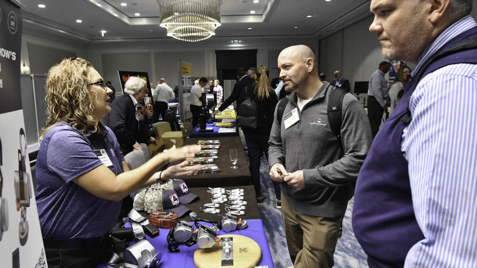 trade show attendees talk to each other over a table