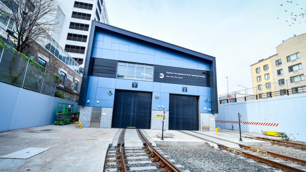 Exterior view of the Railcar Acceptance and Testing Facility with tracks leading into the closed bay doors.