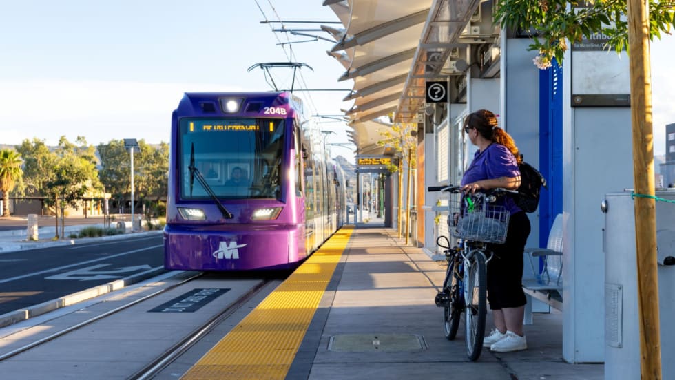 A woman with a bike waits on a rail platform for an incoming train.