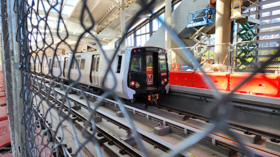 A WMATA train through a chain link fence.