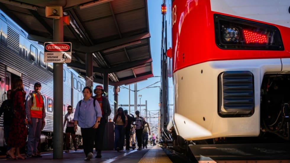 Low view of a Caltrain platform with a train parked at it with passengers nearby.