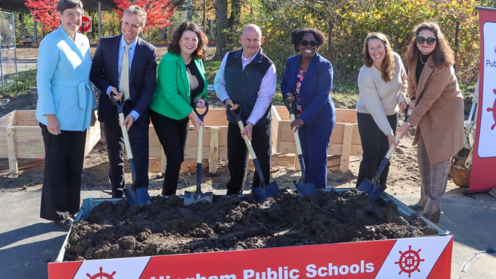 A group of people stand with shovels in dirt.