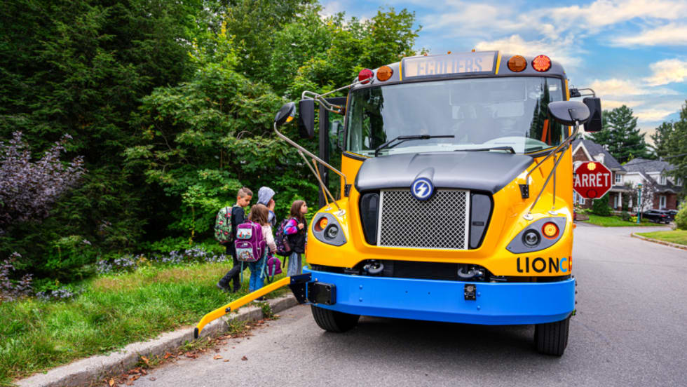 A Canadian LION school bus picks up students at a bus stop.