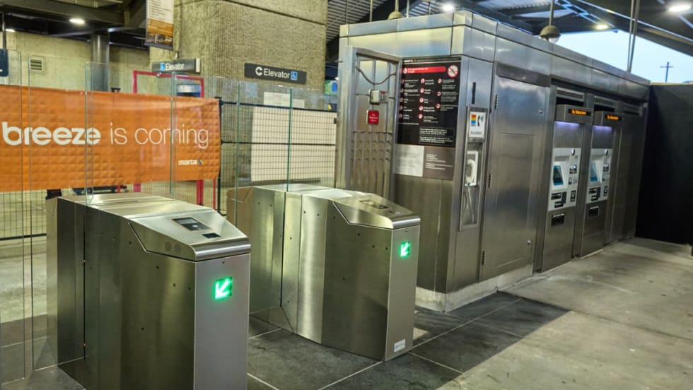 Image of fare gates with an orange sign reading "A better breeze is coming."