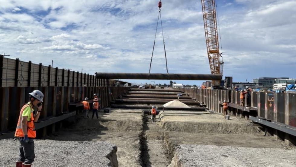 Construction workers guide material hanging from a crane.