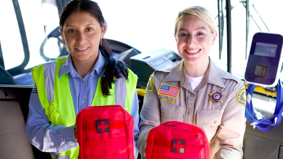 Two female workers hold up NARCAN emergency treatment kits. 