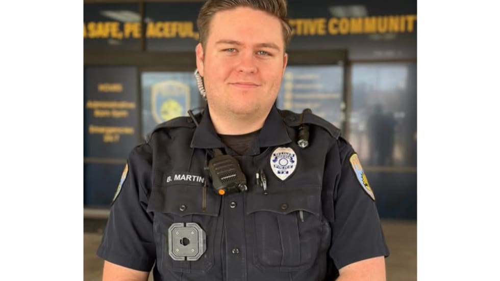 Police officer in dark uniform standing in front of community center backdrop