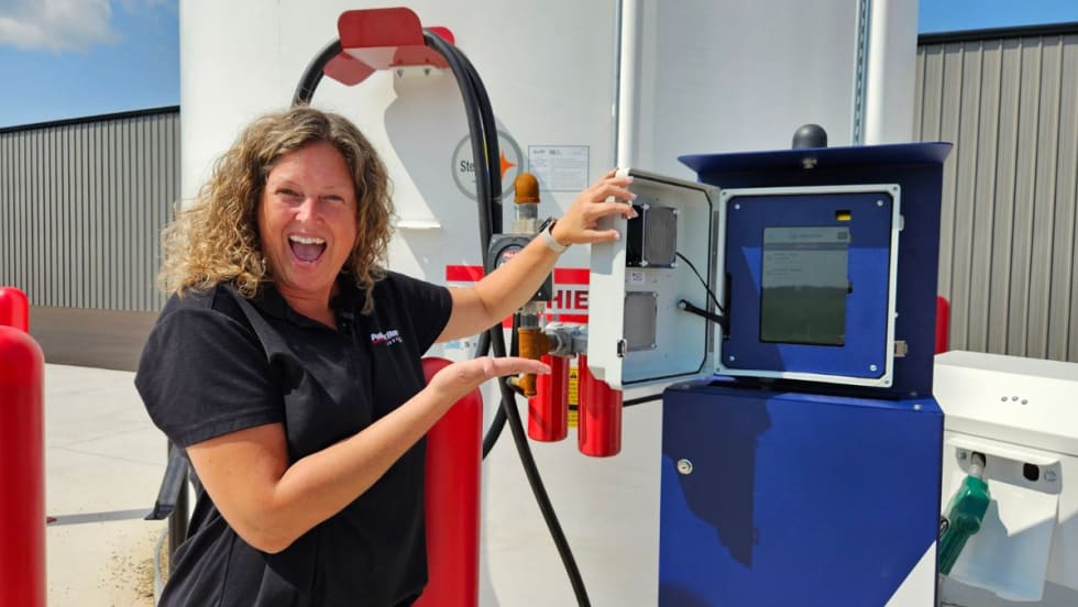 a woman stands in front of fuel tanks