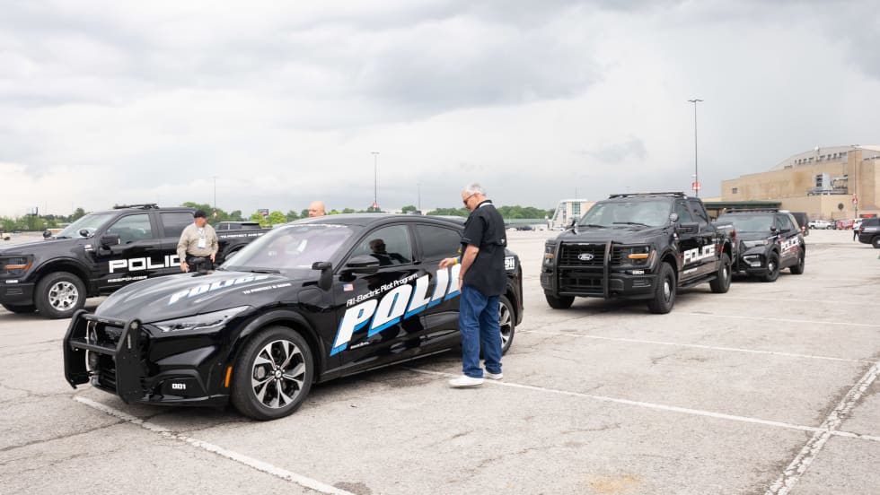 A lineup of police vehicles waiting to be test-driven is shown. They include a Ford Mustang Mach-E, a Ford F-150 Police Responder, and a Ford Police Interceptor Utility.
