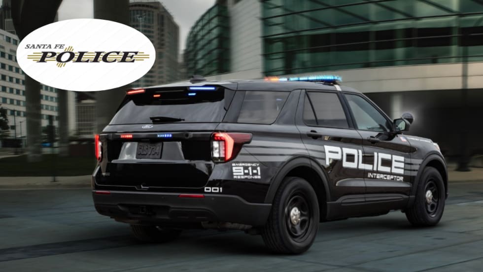 A black Ford Police Interceptor Utility is shown driving down a road.