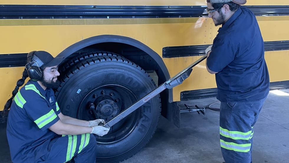 two men work on a school bus