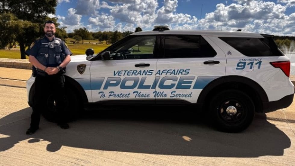 Veterans Affairs Police SUV with officer standing beside white patrol vehicle on sunny day