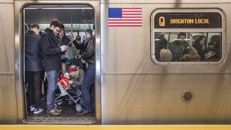 Side view of a subway car with the door open and passengers on board.
