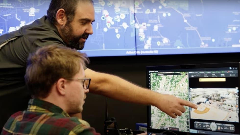 Analysts reviewing geospatial data on multiple computer screens in a monitoring center