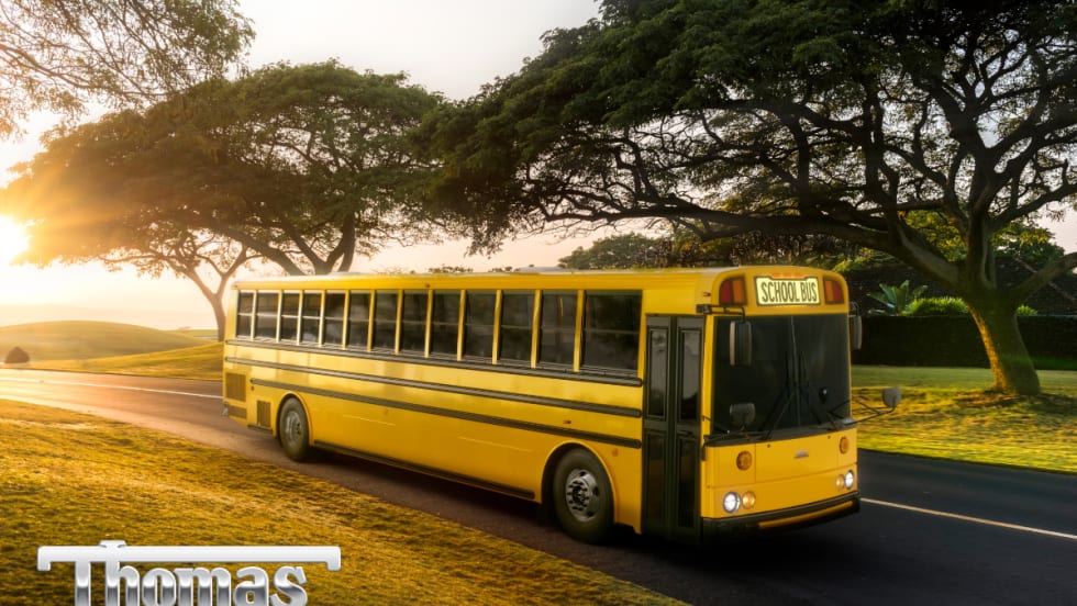 A yellow Thomas Built HDX2 type D school bus is seen driving down the road.