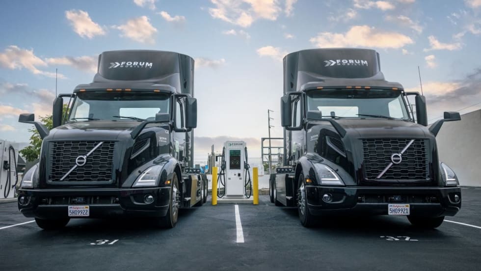 photo of two Volvo electric trucks at a Forum Mobility charging station